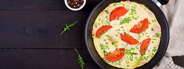 Omelet met tomaten, ham en groene ui op donkere tafel. Frit - Foto, afbeelding