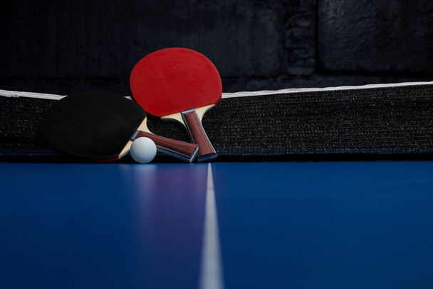 Two ping pong rackets. Table tennis rackets and a ball on a blue tennis table - Foto, Imagen