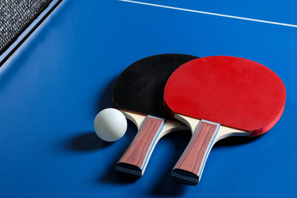 卓球ラケット2台。卓球ラケットと青いテニステーブルのボール - 写真・画像