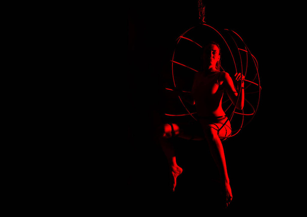 silhouette of sexy woman in red light on a dark background. leggy woman in a bodysuit with metal rings. free space for text - 写真・画像