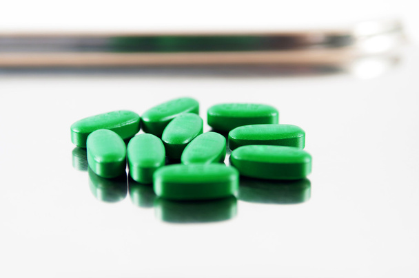 Vihreä tabletti metallin annostelualustalla
 - Valokuva, kuva
