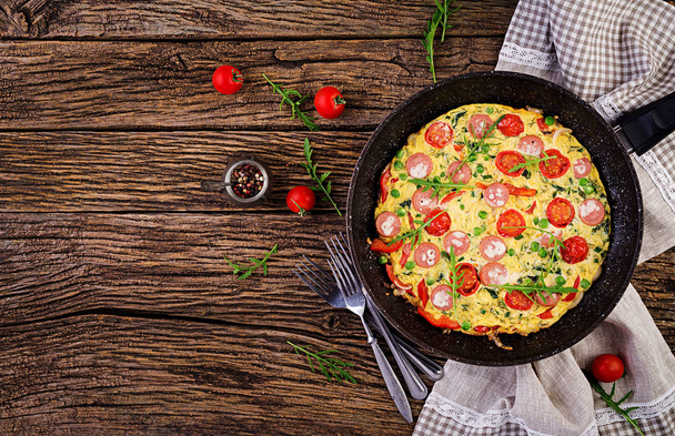 Omelet met tomaten, worst en groene erwten in rustieke stijl. Frittata-Italiaanse omelet. Top View - Foto, afbeelding
