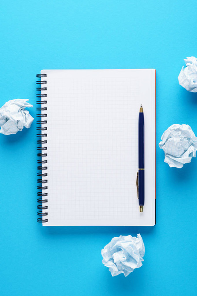 Open notebook, pen and crumpled paper balls on blue background. - Valokuva, kuva