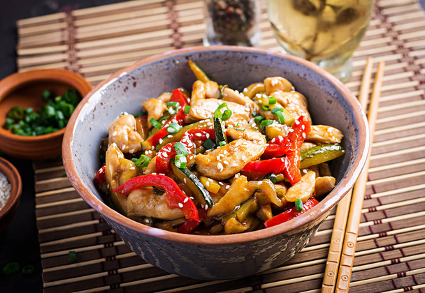 Revuelva el pollo frito, calabacín, pimientos dulces y cebolla verde. Cocina asiática
 - Foto, imagen