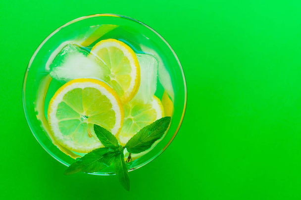 ein Glas Limonade mit Minze auf hellgrünem Hintergrund. Kühlgetränk. Sommer. Blick von oben. Kopierraum. - Foto, Bild