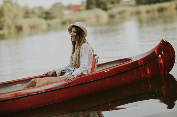 Pretty young woman in the canoe on the lake at summer day - Photo, Image