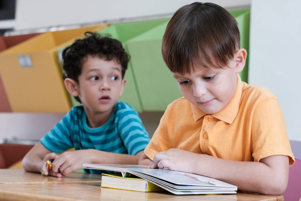 Boy reading book in their kindergarten classroom, kid education  - Fotografie, Obrázek