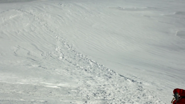 Kiipeilijä kiipeää ylös lumisella rinteellä. nousu Kazbek vuorella aurinkoisena tuulisena päivänä
. - Materiaali, video