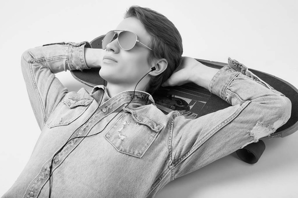 schöner Hipster-Mann in Jeansjacke und Sonnenbrille liegt auf einem Tisch - Foto, Bild