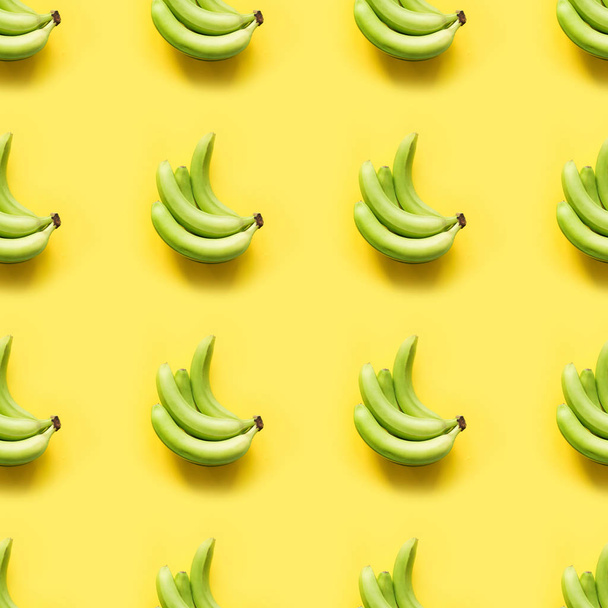 Sweet fresh green banana on punchy pastel yellow background. Top view. Seamless pattern. - Photo, Image