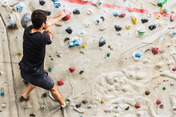 Hombre practicando escalada en roca en paredes artificiales en interiores. Activo
  - Foto, Imagen