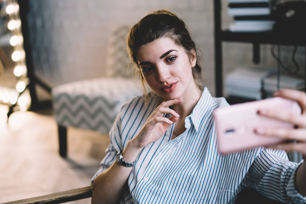Positive female blogger shooting selfie video for publish at own website using 4g wireless and smartphone application, pretty hipster girl making online conference with followers from social network - Foto, immagini