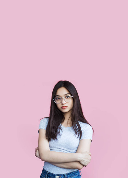 confiante menina asiática de pé com braços cruzados e olhando para a câmera no fundo rosa
 - Foto, Imagem