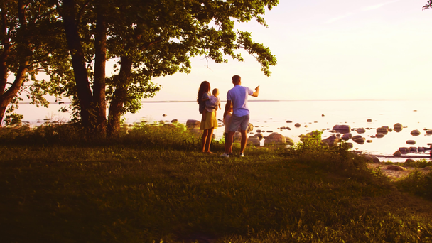 Szczęśliwy rodzinny spacer w pobliżu morza. Pole i drzewa na wsi. Ciepłe kolory zachodu słońca lub wschodu słońca. Kochający rodzice i piękne dzieci. Koncepcja miłości i rodzicielstwa. - Materiał filmowy, wideo