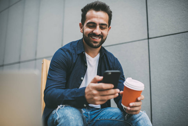 Happy male blogger feeling good from online communication with virtual friends and followers from web page, positive hipster person smiling during messaging via application on mobile gadget - Zdjęcie, obraz