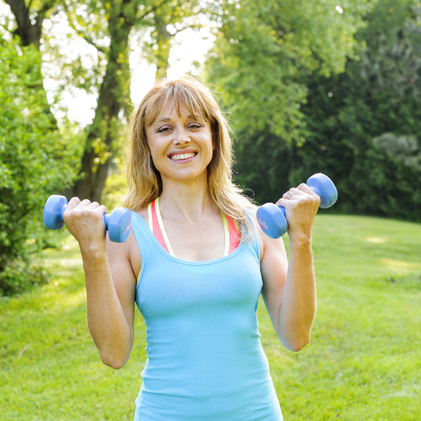 Woman exercising with dumbbells - Fotó, kép