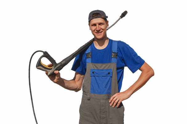 A car wash worker with equipment isolated on a white background. The cheerful guy in overalls looks in the camera and smiles. Layout or background with space for copy - Photo, Image