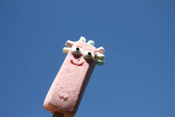 мороженое на палочке с лицом и голубым небом
 - Фото, изображение