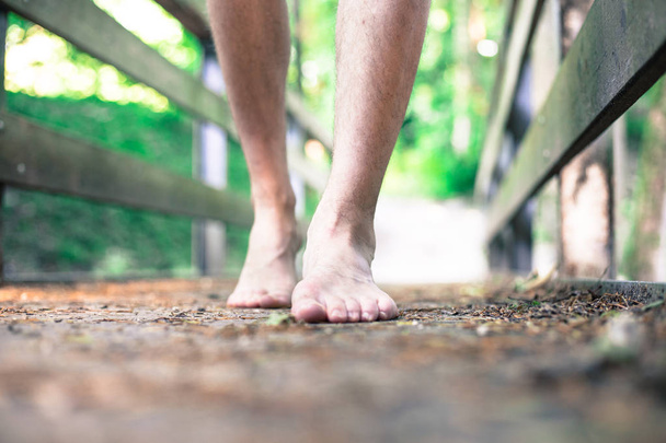 Forest adventure: Closeup of barefoot male feet on a wooden brid - Photo, Image