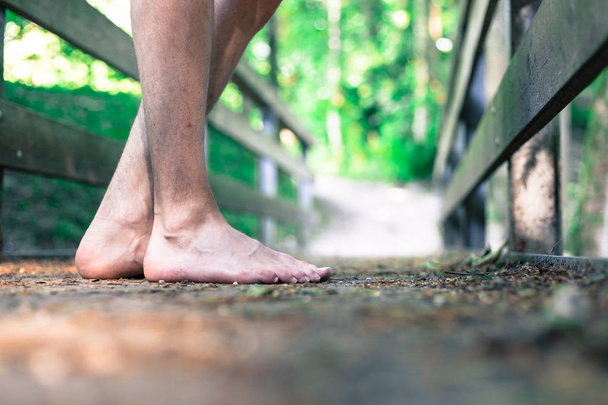 Forest adventure: Closeup of barefoot male feet on a wooden brid - Zdjęcie, obraz