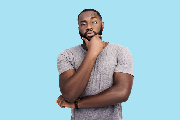 serious handsome black man touching chin on blue background - Photo, Image