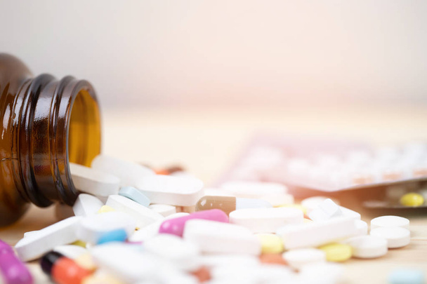 Bottiglia di pillola che fuoriesce. pillole colorate su tavolette superficiali su uno sfondo di legno tavolo. vista dall'alto. concetto di assistenza sanitaria medica farmacologica
 - Foto, immagini