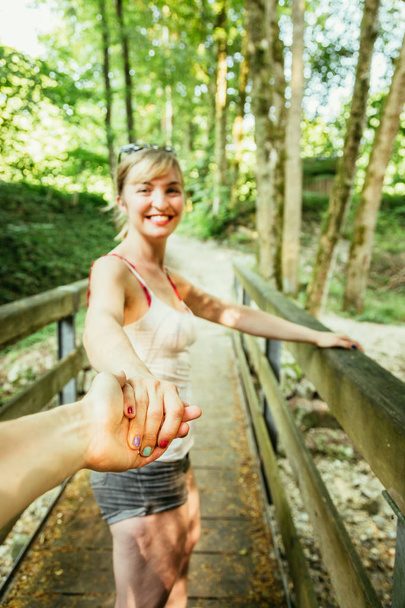 Adventure in the woodland: Girl is holding her boyfriends hand f - Foto, afbeelding