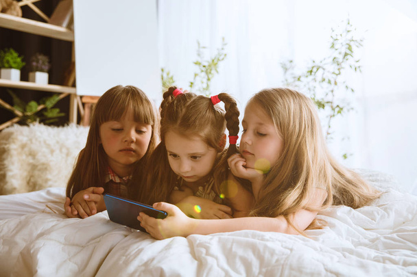Little girls using different gadgets at home - Foto, imagen