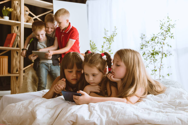 Little boys and girls using different gadgets at home - Foto, imagen