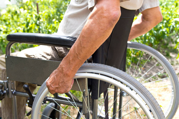 Een gehandicapte man zit in een rolstoel, houdt zijn handen op th - Foto, afbeelding