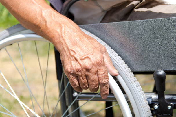 Інваліда людина сидить в інвалідному візку, тримає руки на Че - Фото, зображення