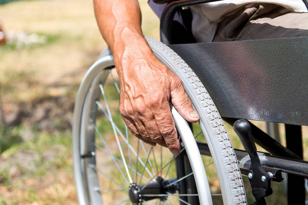 A fogyatékossággal élő ember ül a kerekesszékben, tartja a kezét a - Fotó, kép