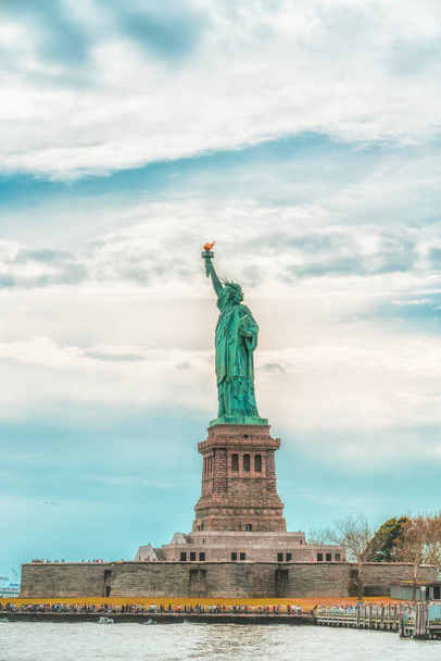 曇り青い空の背景に対する自由の島の自由のニューヨーク市の像。コピースペース、愛国心、旅行コンセプト。垂直バナー - 写真・画像