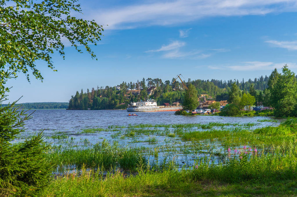 Summer landscape with pier and small harbour in northern village. Ladoga lake bay in sunny day. Beautiful rural scenery, travel blog concept. Lahdenpohja, Karelia, Russia - Photo, Image
