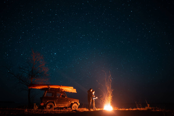 Feliz pareja hombre y mujer de pie en frente de hoguera ardiente
 - Foto, Imagen