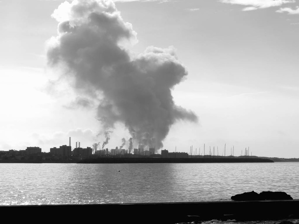 Teollinen maisema rannikolla. Ilmansaasteet tehtaan savupiiput. Musta ja valkoinen kuva
 - Valokuva, kuva