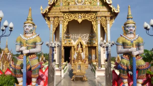 アジアの寺院の近くにカラフルな彫像。東洋の国の晴れた日に観賞用の仏教寺院の近くに位置する2つの明るい多色の彫像。ワット・プレイ・レムの神話の巨大な守護者ヤク。サムイ. - 映像、動画