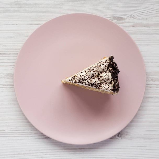 Шматок тірамісу на рожевій тарілці на білому дерев'яному фоні
 - Фото, зображення