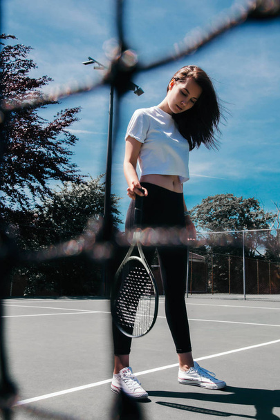 Sporty young woman posing with tennis racket on tennis court - Foto, Imagem