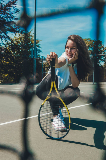 Sporty young woman posing with tennis racket on tennis court - Foto, Imagem