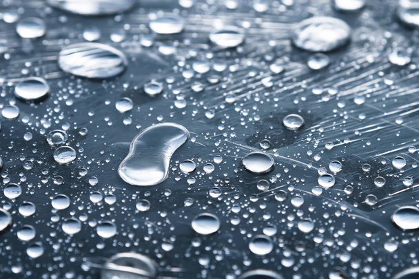 Close-up de gotas de chuva de diferentes tamanhos na superfície coberta com filme aderente. Tempo de umidade e conceito de umidade
 - Foto, Imagem