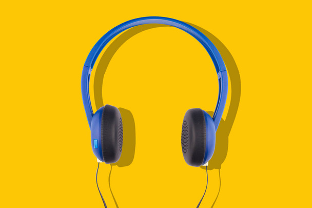 auriculares azules aislados sobre fondo amarillo
 - Foto, Imagen