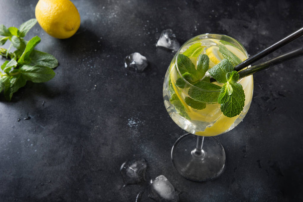 Detox water or lemonade with lemon and mint in glass on black table. Close up. Summer drink. - Fotografie, Obrázek