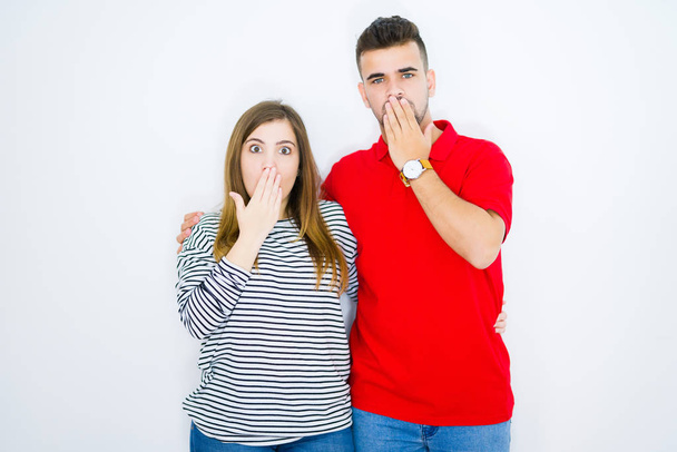 Young beautiful couple hugging together over white isolated background cover mouth with hand shocked with shame for mistake, expression of fear, scared in silence, secret concept - Photo, Image
