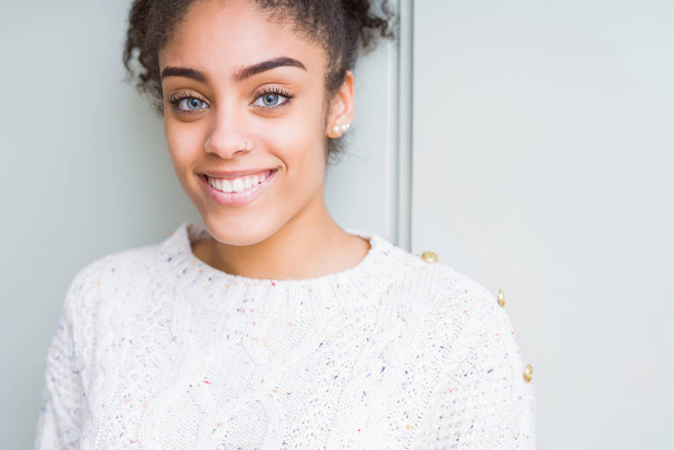 Красива молода афроамериканець жінка з афро волосся носять випадковий светр з щасливою і прохолодною посмішкою на обличчі. Щаслива людина. - Фото, зображення