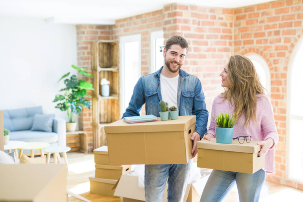 Joven hermosa pareja muy feliz juntos sosteniendo cajas de cartón moviéndose a un nuevo hogar
 - Foto, Imagen