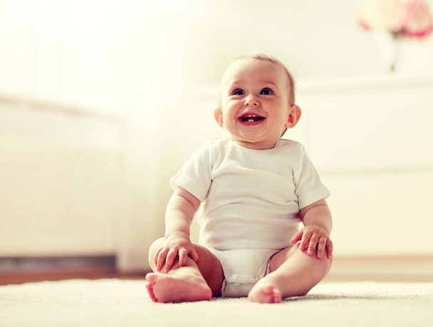 happy baby boy or girl sitting on floor at home - Фото, изображение