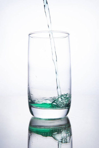 Green cocktail is poured into a glass on a white background with - 写真・画像