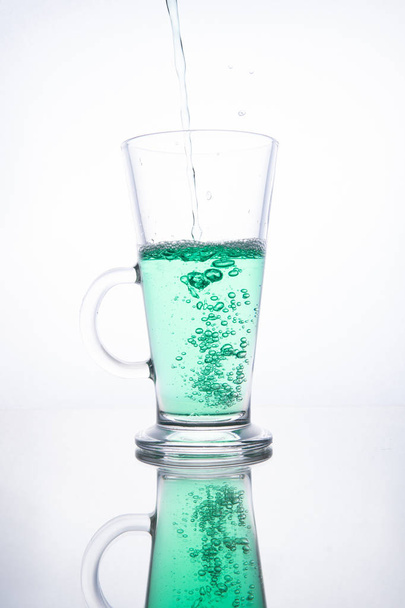Green cocktail is poured into a glass on a white background with - Фото, зображення