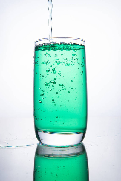 Green cocktail is poured into a glass on a white background with - Valokuva, kuva